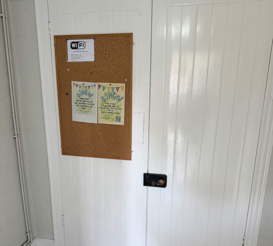 The hall's entrance doors with a cork noticeboard showing event posters and Wi-Fi details